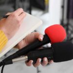Record-Breaking NFL star reveals ALS diagnosis at age 39 Journalist holding two microphones while writing in a notebook