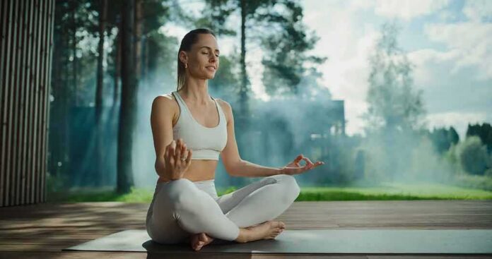 shutterstock_2614146269 Woman meditating outdoors in a seated yoga pose