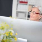 Older woman with gray hair wearing glasses at a desk