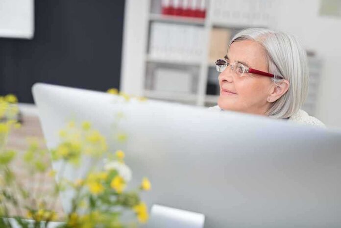 Older woman with gray hair wearing glasses at a desk
