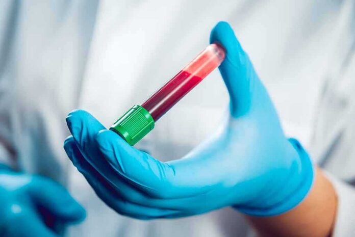 shutterstock_326298614 Gloved hand holding a blood sample tube
