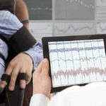 Blood Sugar Hacks That Make You Immune to Carbs Technician reviews polygraph readings on a tablet beside a seated subject