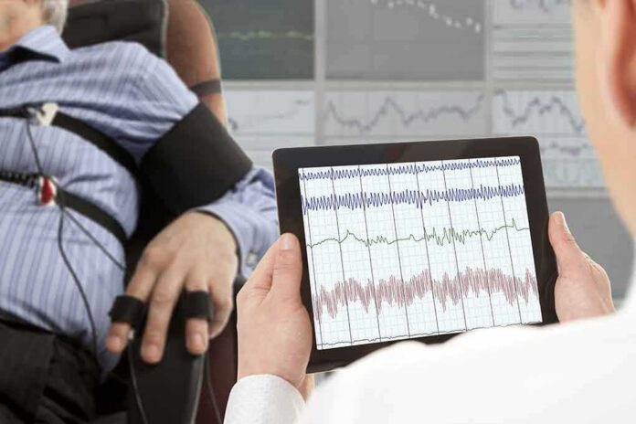shutterstock_327795071-5 Technician reviews polygraph readings on a tablet beside a seated subject
