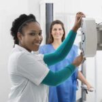 AI Turns Breast X-Ray Into Heart Alarm Radiologic technologist adjusting X-ray machine with patient standing behind