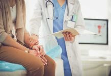 The Urination Habit That Could Be Messing Up Your Bladder Doctor comforting patient while reviewing medical chart