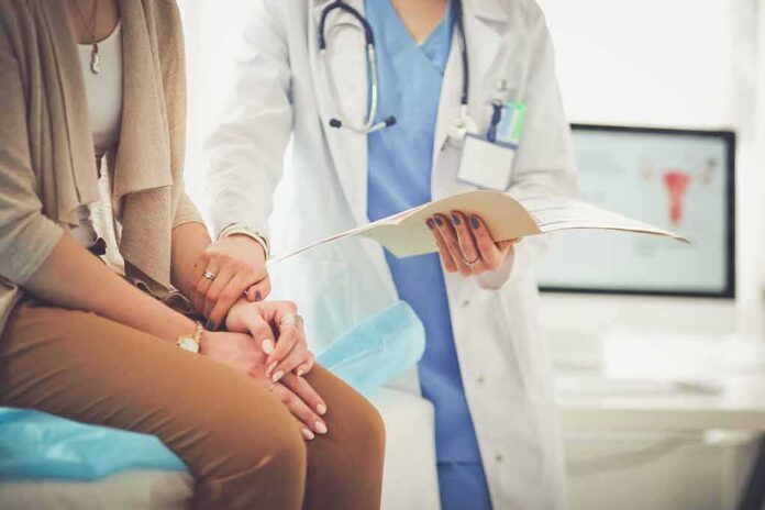 shutterstock_696188545-1 Doctor comforting patient while reviewing medical chart