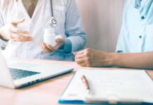 Doctor showing a pill bottle to a patient during consultation