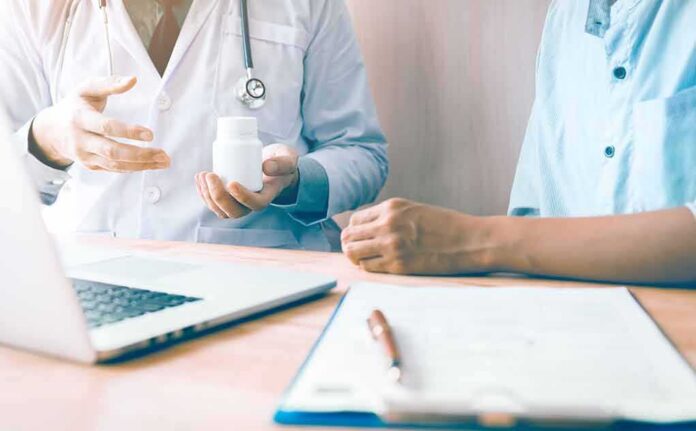 Doctor showing a pill bottle to a patient during consultation