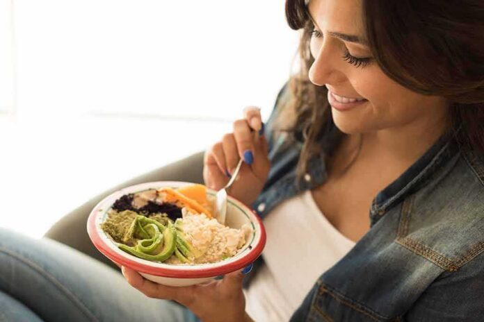 Woman eating a bowl of rice and vegetables