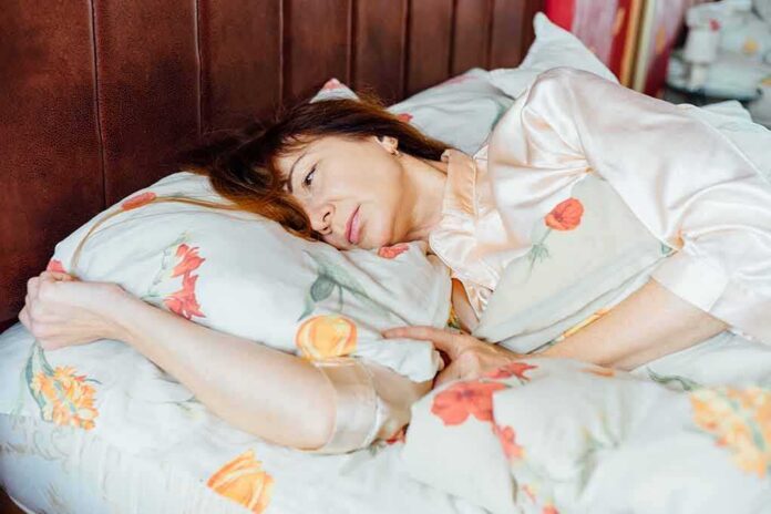 1783887599307-5d9s4p-shutterstock-583468087 woman lying in bed looking pensive