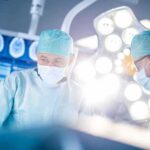 Old Man Disease Ambushing Young Men Surgeons in operating room under bright surgical lights