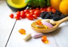 Dietary Supplements: High-Dose Dangers Wooden spoon holding assorted vitamin pills beside fresh fruits and vegetables