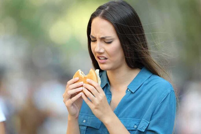 shutterstock_1134594305 Woman looking displeased at a hamburger outdoors