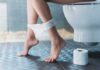 Person sitting on a toilet with underwear at ankles and toilet paper nearby