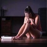 Weight Loss Stalling: Here’s The Sneaky Culprit Woman sitting on floor covering face beside a bathroom scale