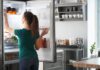 Woman reaching into an open refrigerator in a modern kitchen