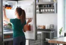 Woman reaching into an open refrigerator in a modern kitchen