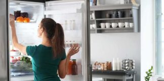 Woman reaching into an open refrigerator in a modern kitchen