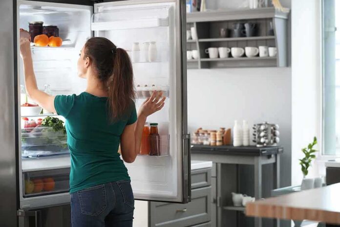 shutterstock_1390969019 Woman reaching into an open refrigerator in a modern kitchen