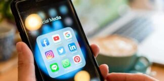 Hands holding a smartphone showing social media app icons