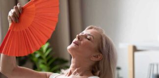 Woman fanning herself with an orange hand fan