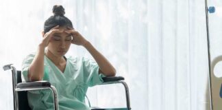 Woman in a wheelchair holding her head