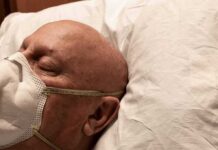Elderly man wearing a face mask resting on a pillow