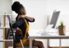 Woman at desk rubbing her neck and lower back