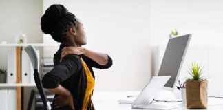 Woman at desk rubbing her neck and lower back