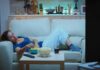 Woman lounging on a sofa watching TV at night