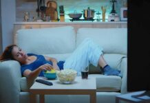 Woman lounging on a sofa watching TV at night