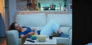 Woman lounging on a sofa watching TV at night