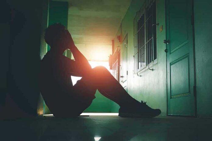Person sitting on hallway floor with head in hands at sunset