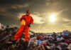 Person in protective gear standing on a landfill with a yellow container