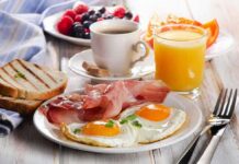 Fried eggs with bacon, toast, coffee, and orange juice on a breakfast table