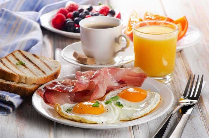 Fried eggs with bacon, toast, coffee, and orange juice on a breakfast table