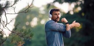 man stretching his arm outdoors while wearing headphones