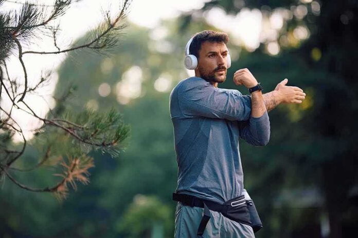 shutterstock_2648580983 man stretching his arm outdoors while wearing headphones