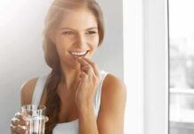 Woman holding a glass of water and taking a pill