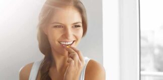 Woman holding a glass of water and taking a pill