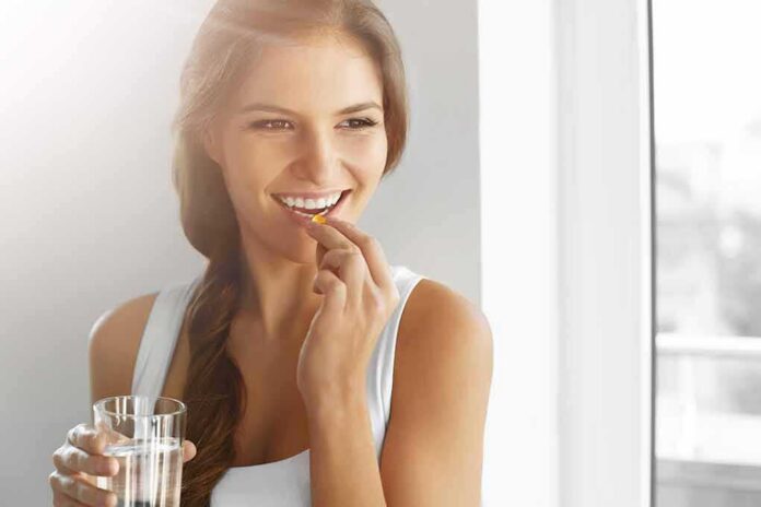 Woman holding a glass of water and taking a pill