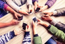 Smartphones Are The Problem, Not Social Media Hands around a table holding smartphones