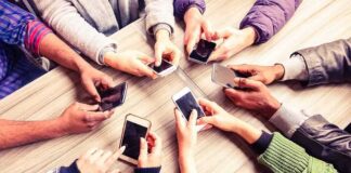 Hands around a table holding smartphones