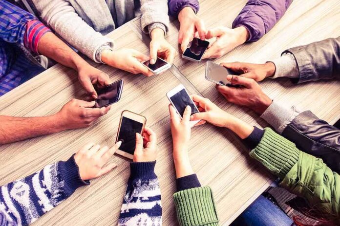 shutterstock_393607117 Hands around a table holding smartphones