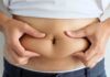 person pinching belly fat at the waist