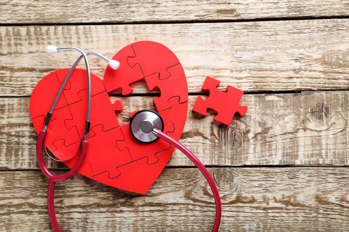 Red heart puzzle with stethoscope on wooden surface