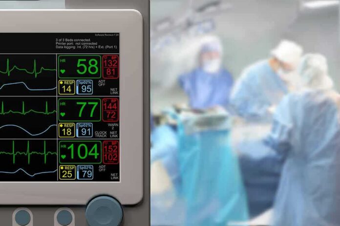 patient monitor beside blurred surgeons in an operating room