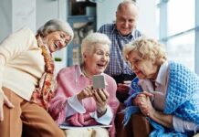 Group of seniors smiling and looking at a smartphone together