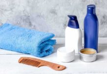 bathroom toiletries with blue towel and wooden comb on white surface