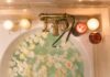 Bathtub filled with water and white roses under candles